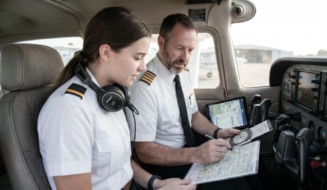 A student pilot and her instructor reviewing a chart in the cockpit