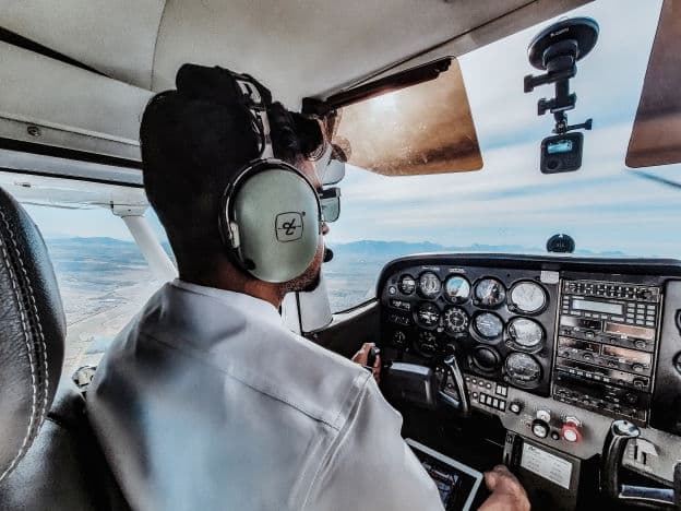 A student pilot in a headset flying the aircraft, hands on the controls