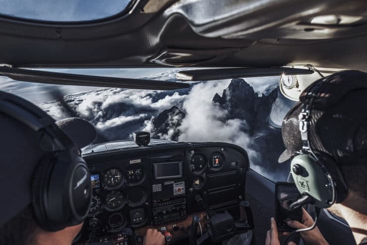 The view past a pilot's headset over a layer of cloud on a cross-country flight
