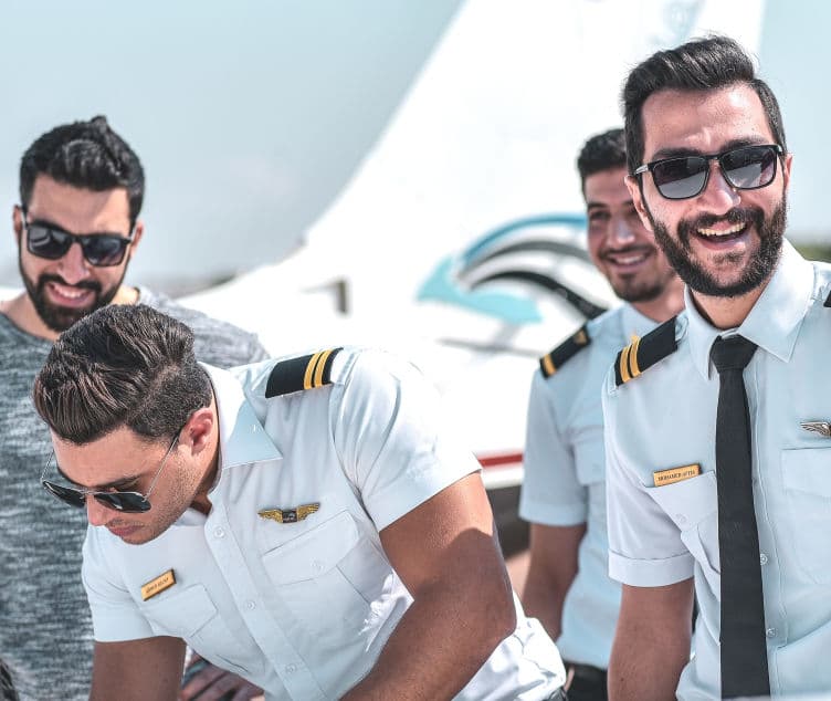 Smiling student pilots gathered beside an aircraft on the apron