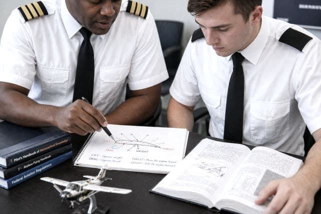 Two student pilots in uniform working through a flight-planning exercise together