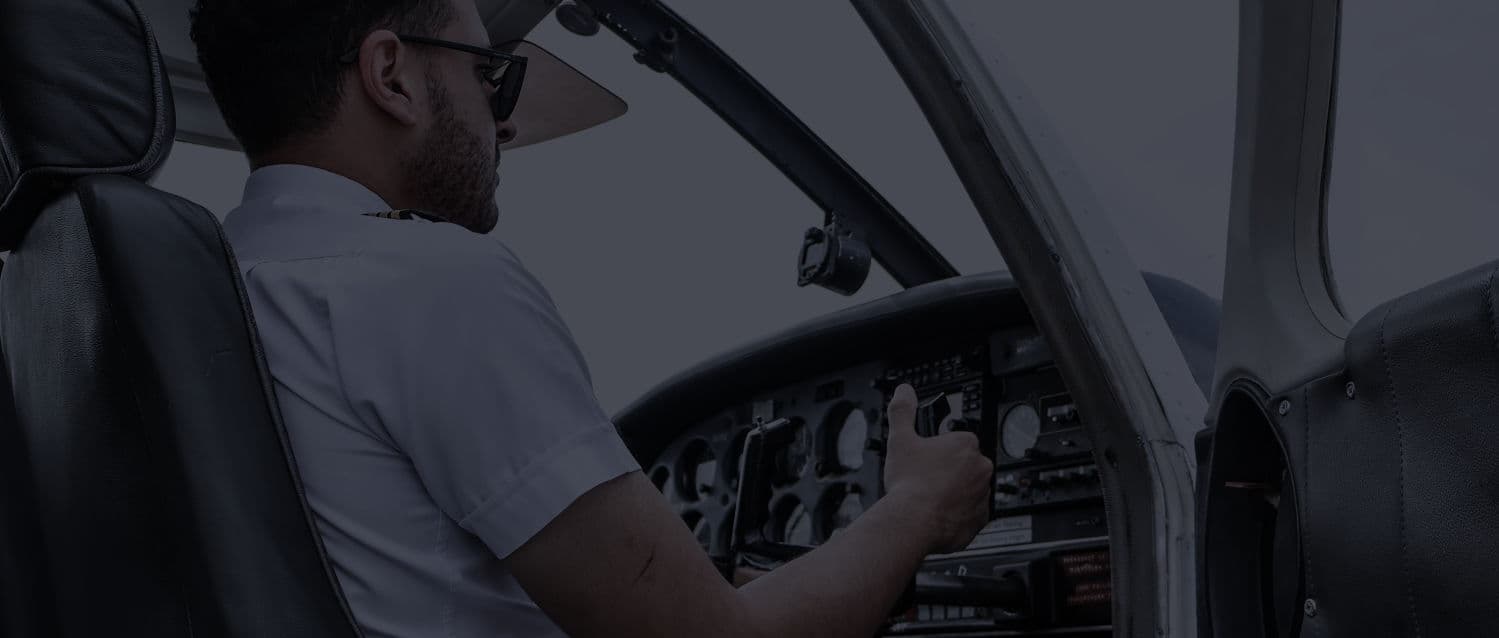 An instructor at the controls of a training aircraft, lit by the instrument panel